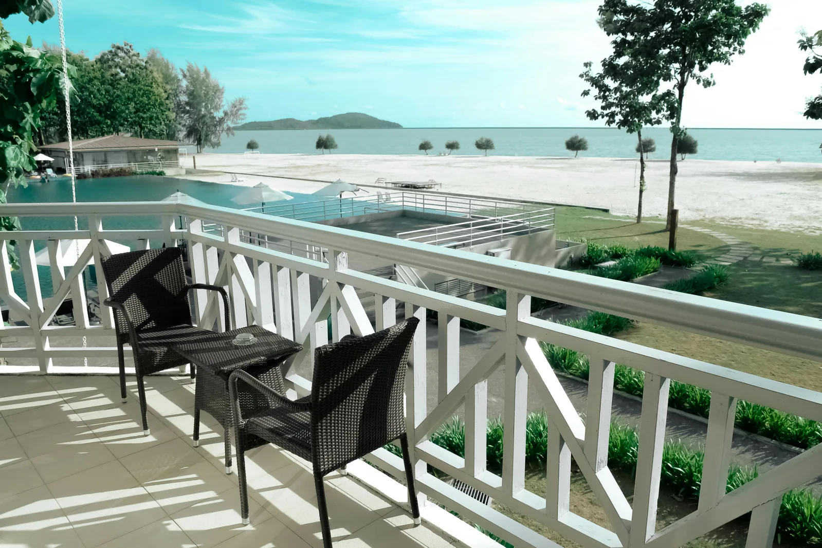 Balcony seating overlooking a beach and pool.