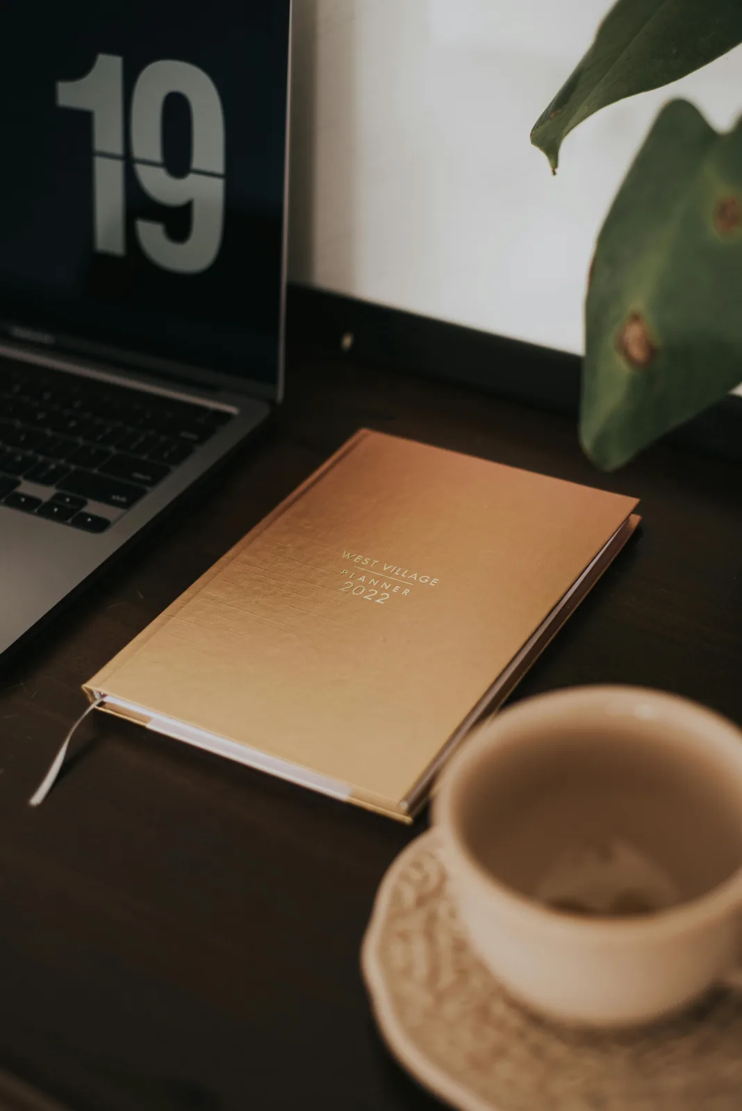 Coffee and notebook next to a sleek laptop.